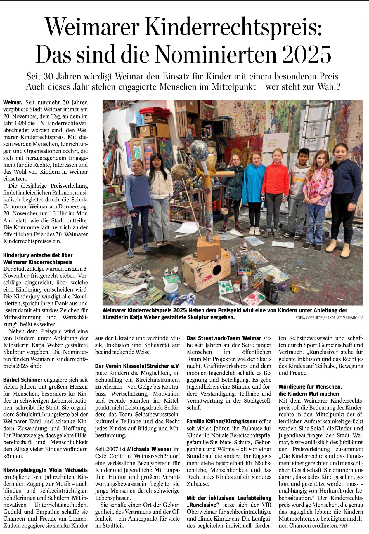 Group of children standing in an art studio around a colorful, mixed-media sculpture created under the guidance of artist Katja Weber.